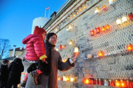 Sieviete ar bērnu noliek sveci pie Rīgas mūra 11.Novembrī